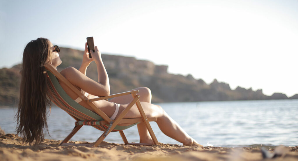 woman enjoying the beach while using cell phone